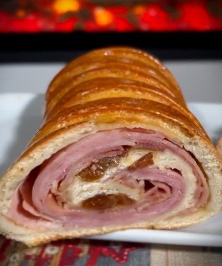 Sliced ham and raisin bread roll displayed on a white plate.