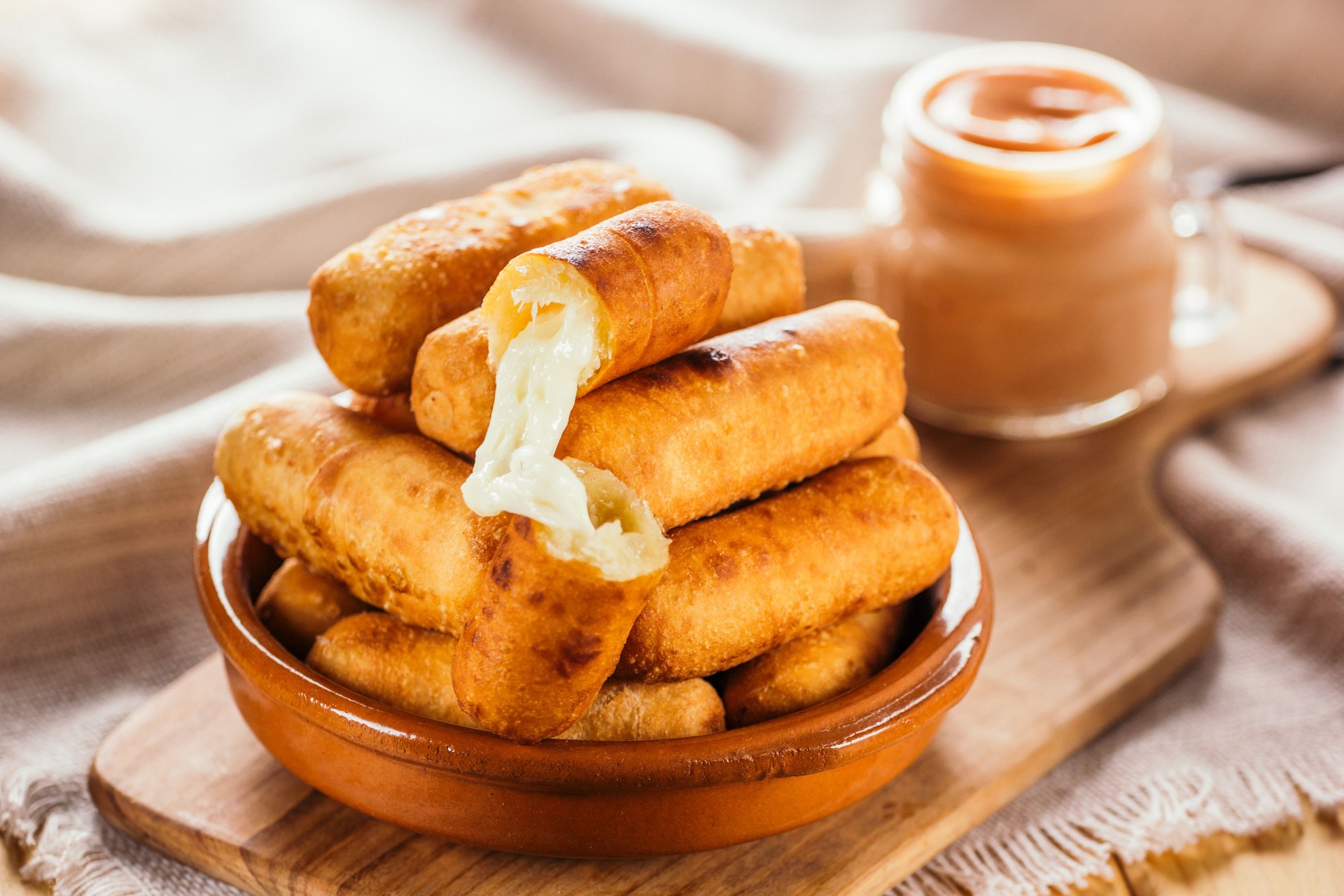 Dedos de queso aperitivo típico venezolano llamado tequeños acompañados con una salsa rosa en un tablero de madera